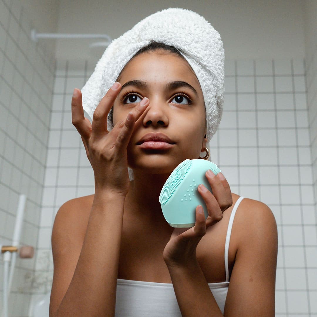 Giovane donna applica detergente per pulire il viso con SONIC FACIAL CLEANSER
